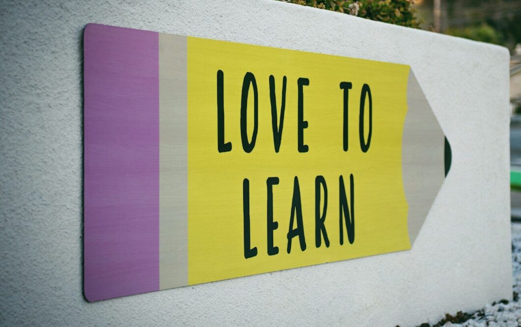 love to learn pencil signage on wall near walking man